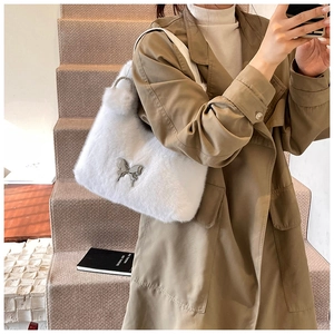 Close-up of plush white faux fur shoulder bag featuring a silver metal butterfly ornament