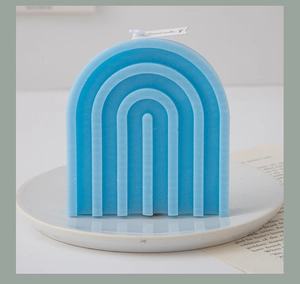 Macro shot of blue rainbow arch scented candle on ceramic tray with minimalist decor