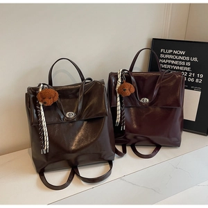 Detail of vintage faux leather backpacks in brown and wine red with plush puppy charms