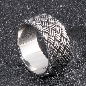 Vue macro d'une bague large en acier inoxydable avec texture tressée vintage et fini oxydé
