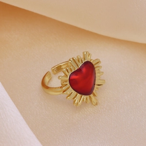 Macro shot of 18k gold plated ring featuring red heart-shaped gemstone on beige silk
