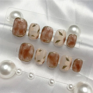 Detail of amber marble and floral press-on nails set on white silk with pearls