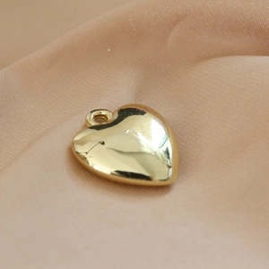 Detailed view of a polished golden heart-shaped resin pendant on soft beige silk fabric
