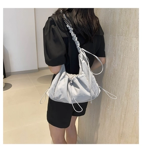 Detail of light gray ruffled shoulder bag showing canvas texture and drawstring design