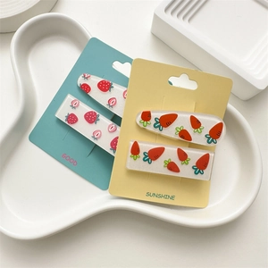 Detail view of strawberry and carrot hair clips set on colorful display cards