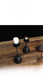 Detail view of rustic cast iron candle holders with textured finish on a wooden table