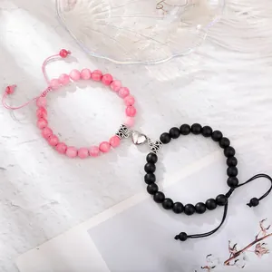 Magnetic tiger eye stone bracelets for couples with heart charm on white marble base