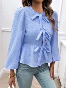 Detail of blue plaid shirt featuring three delicate bow ties and a cinched waist design