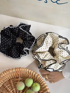 Detailed close-up of black and white polka dot scrunchies with elegant ruffled edges