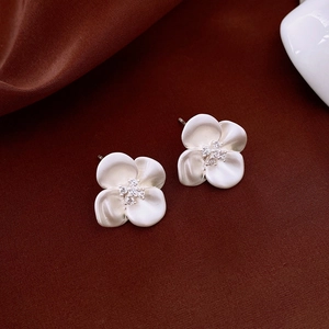 Macro view of silver flower stud earrings with sparkling crystals on velvet background