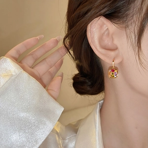 Detail of 18k gold plated drop earrings with colorful square zircons on female model