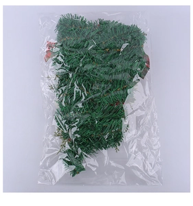 Detail of creative green Christmas wreath inside packaging with a plaid bow accent