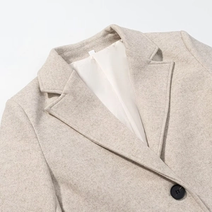 Detail of oat wool coat featuring a notch lapel, smooth white lining, and black button