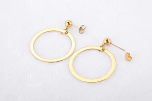 Detailed view of hollow geometric gold round earrings with metallic finish on fabric
