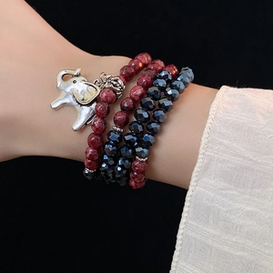 Detail of multi-layer beaded bracelet with red stone beads and silver elephant charm