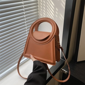 Minimalist caramel brown trapezoid leather handbag with round handle and shoulder strap