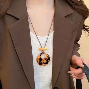 Detail of bohemian long sweater necklace with tortoiseshell resin ring and wooden beads