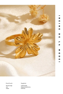 Detail of 18K gold plated flower ring with textured petals on white satin backdrop