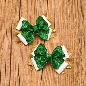 Detail of St. Patrick's Day hair bows with green glitter and gold leaf design on wood