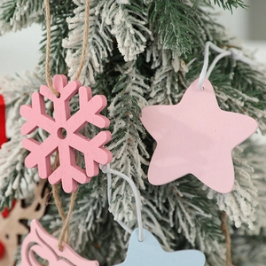 Pastel wooden Christmas tree ornaments with star and deer shapes on snowy branches