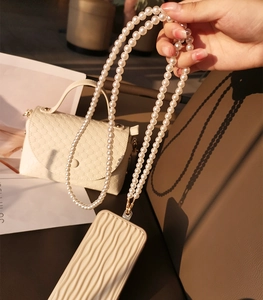 Detail of elegant crossbody pearl strap attached to a cream mobile phone case
