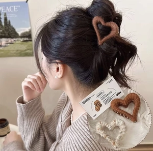 Detail of plush hollow heart claw clip in brown and beige showing a cozy autumn texture