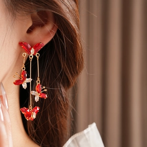 Gros plan de boucles d'oreilles papillon rouges avec pompons et zircons sur mannequin