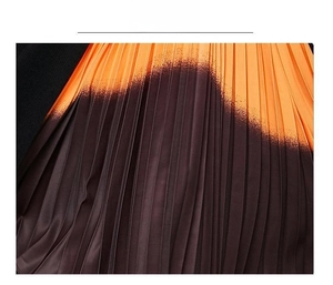 Vue détaillée du tissu plissé dégradé orange et marron foncé avec une texture fine
