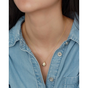 Close-up of a gold teardrop pendant necklace with clear crystals on a model