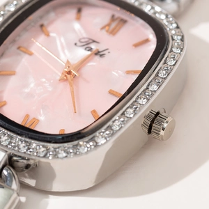 Detailed macro view of silver watch bezel with inlaid crystals and pink marble dial
