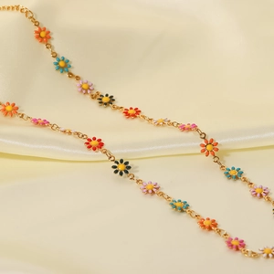Detalle del collar de acero de titanio oro 18K con dijes de margaritas en esmalte
