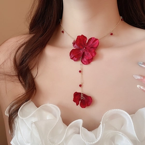 Detail of red fabric flower pendant with crystal beads on a delicate gold chain necklace