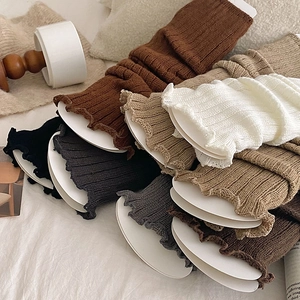 Close-up of knit leg warmers in various colors featuring vertical ribbed textures and ruffles