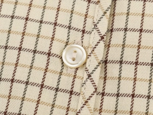 Macro view of plaid shirt fabric with pearlescent white button and neat stitching