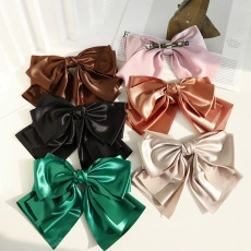 Detailweergave van grote satijnen haarstrikken in diverse kleuren met veerklemmen