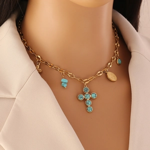 Gros plan détaillé d'un collier doré orné de breloques turquoise, croix et cœurs