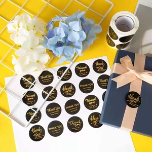 Roll of 500 gold foil Thank You stickers for small business packaging on a blue gift box