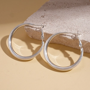 Detail of 18k gold plated brushed metal hoop earrings on a natural stone background
