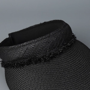 Detailed close-up of black straw woven open top sun hat with fringe decorative trim