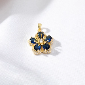 Close-up of gold flower pendant with blue gemstones and micro-pave cubic zirconia