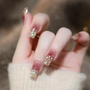 Detailed view of square gradient nails with red-brown tint and sparkling gold glitter