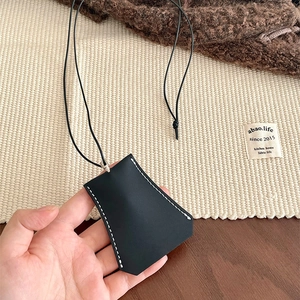 Detail of black faux leather key pouch with contrast white stitching and lanyard cord