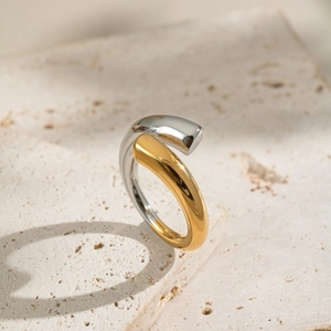 Detailed view of bicolor gold and silver titanium steel ring on a beige stone base