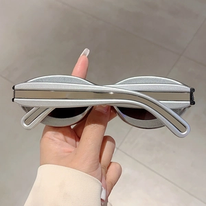 Detail of silver narrow oval sunglasses showing the metallic frame and slim temple design