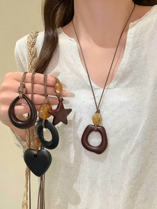 Detail view of heart and star resin pendants on woven rope necklaces in earthy tones