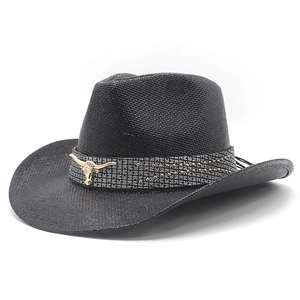 Detail of black straw cowboy hat featuring a vintage gold bull head emblem and rivets