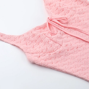 Détail du tissu en dentelle rose avec motifs ajourés complexes et lien de serrage ajustable