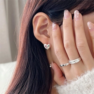Detail of silver heart stud earrings with zircon and matching minimalist heart rings
