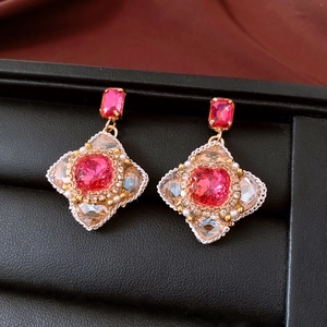 Dettaglio di orecchini vintage con pietre preziose rosa e dettagli in cristallo intrecciato