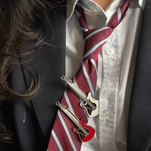 Detail shot of mini electric guitar tie clips in red and white on a striped necktie
